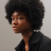 A headshot of a dark-skinned woman with afro hair called Jessica.